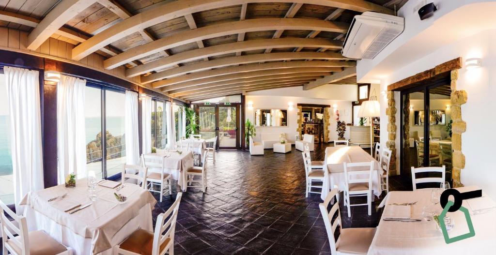 un restaurant avec des tables et des chaises blanches et des fenêtres dans l'établissement Hotiday Apartments Cefalù, à Cefalù