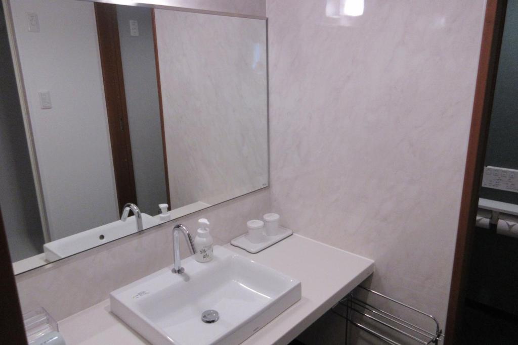 une salle de bain avec un lavabo et un grand miroir dans l'établissement Asagiriso, à Toyooka