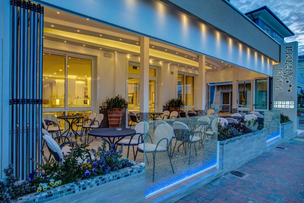un restaurant avec des tables et des chaises sur une terrasse dans l'établissement Hotel Riviera, à Bellaria-Igea Marina