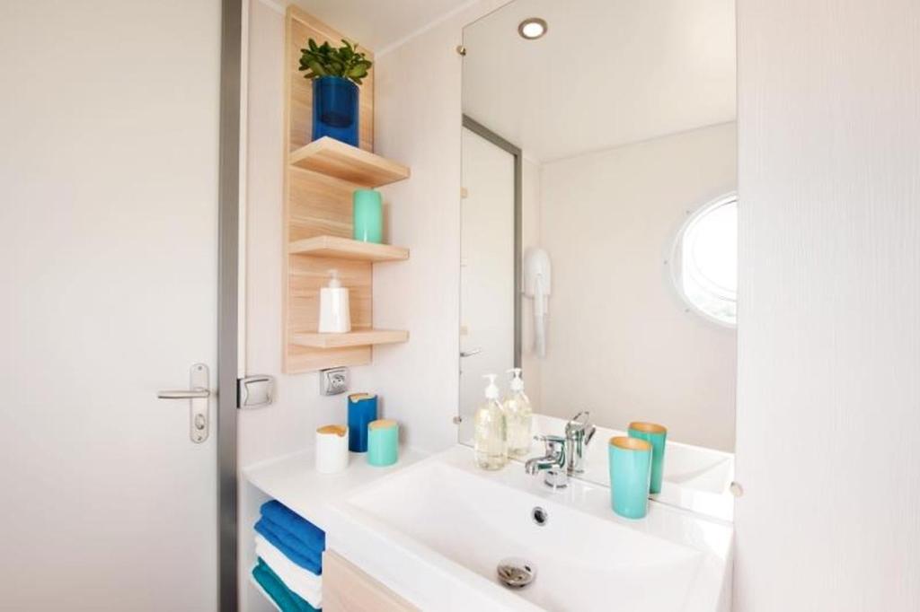une salle de bain avec un lavabo et un miroir dans l'établissement Domaine Résidentiel de Plein Air La Plage, à Treignac