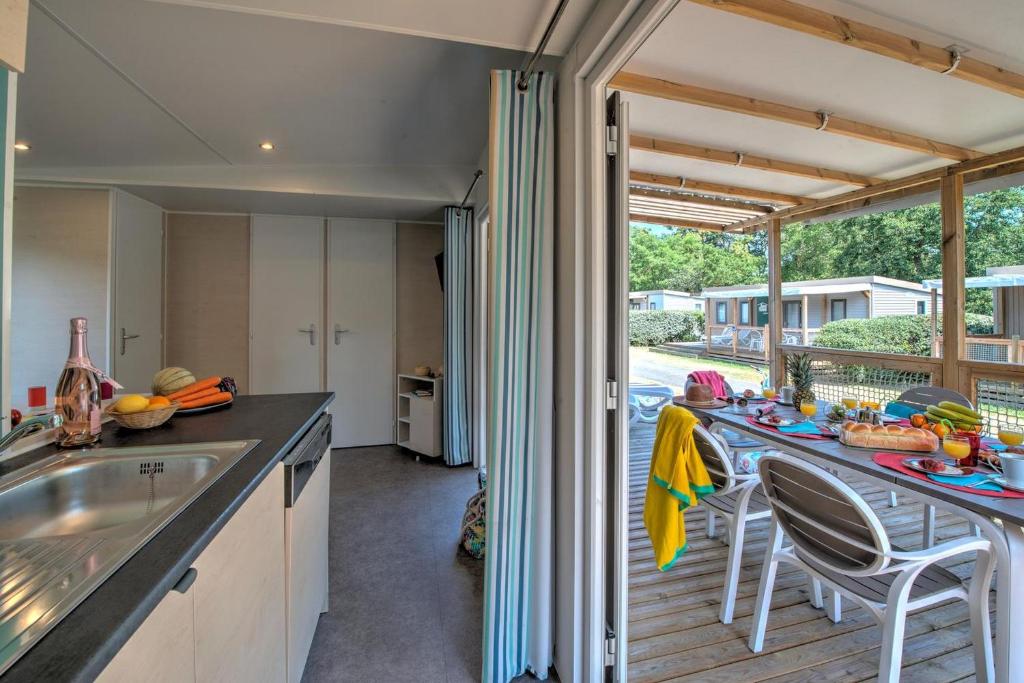 une cuisine avec un comptoir et une table avec des chaises dans l'établissement Domaine Résidentiel de Plein Air L'Île d'Offard, à Saumur