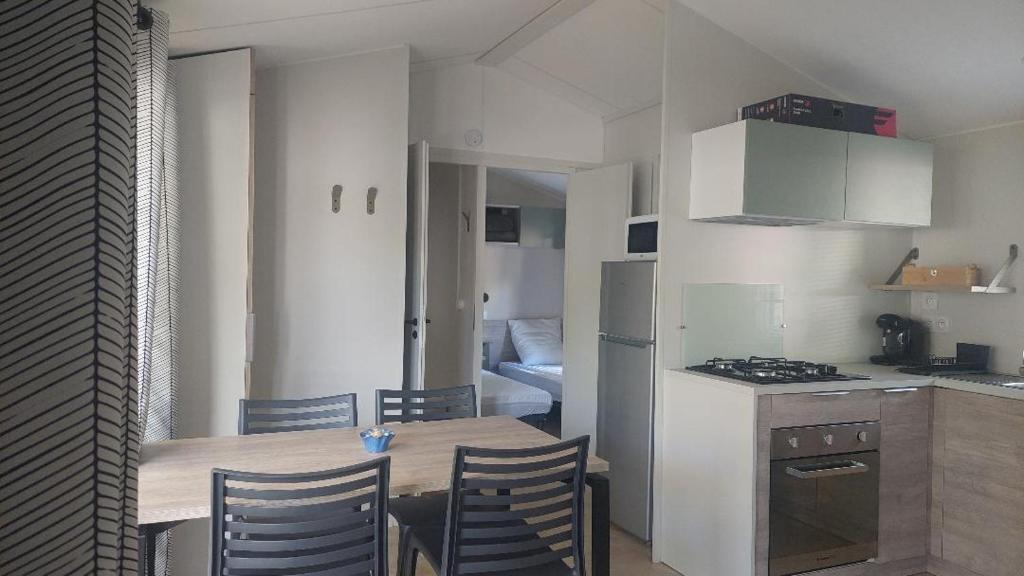 une cuisine avec une table et des chaises dans une pièce dans l'établissement Mobil home prémium 8 pers camping 4 étoiles, à Saint-Cyprien
