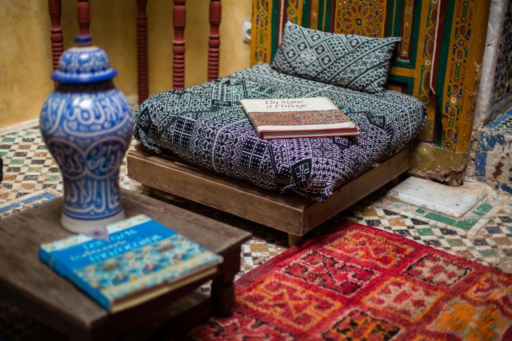 un lit avec un livre et un vase sur une table dans l'établissement Ryad Bahia, à Meknès