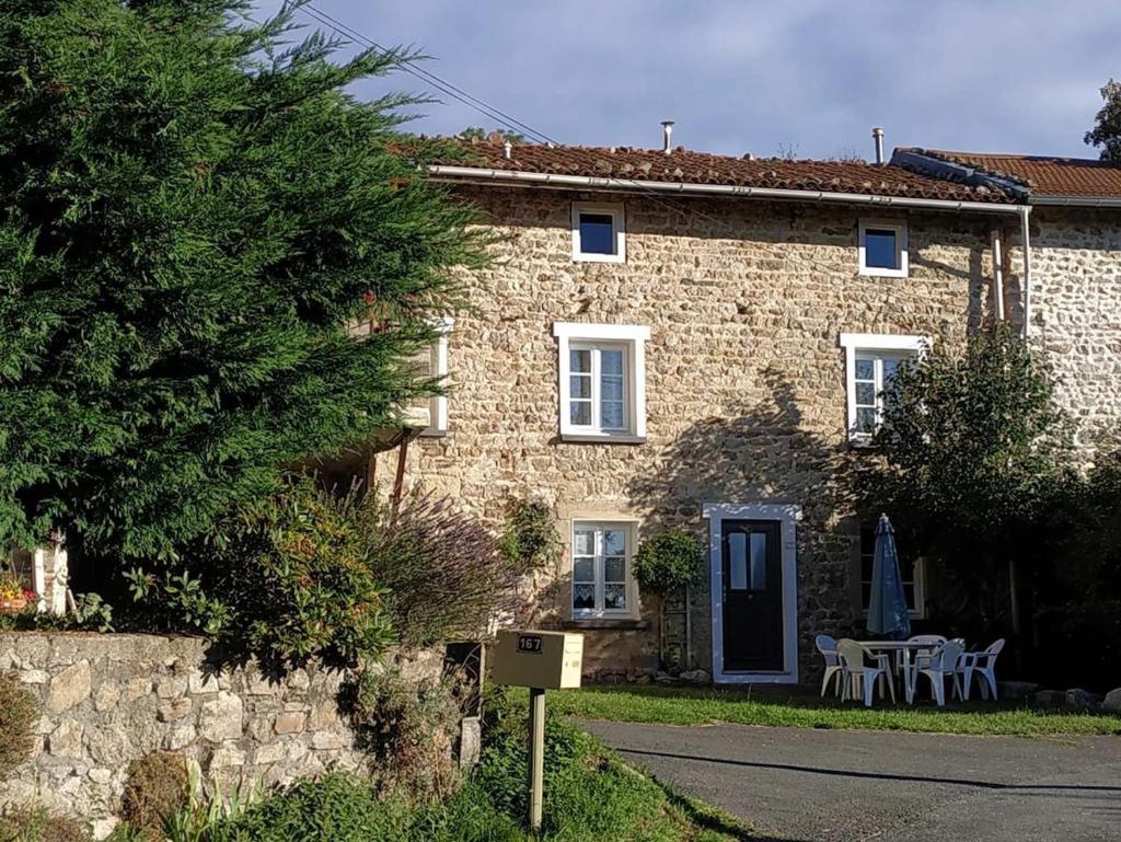 une maison en pierre avec une table et des chaises devant elle dans l'établissement Gîte à CHALMAZEL équipé, dans hameau calme, à Mermond