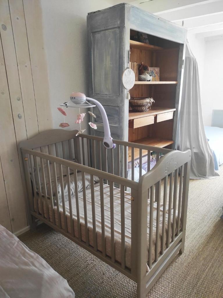- un lit bébé dans une chambre avec commode dans l'établissement Gîte à CHALMAZEL équipé, dans hameau calme, à Mermond