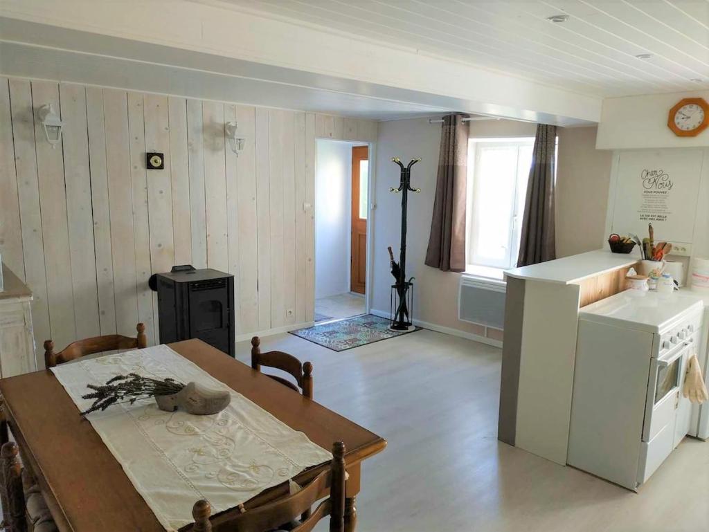 une cuisine et une salle à manger avec une table et un réfrigérateur dans l'établissement Gîte à CHALMAZEL équipé, dans hameau calme, à Mermond