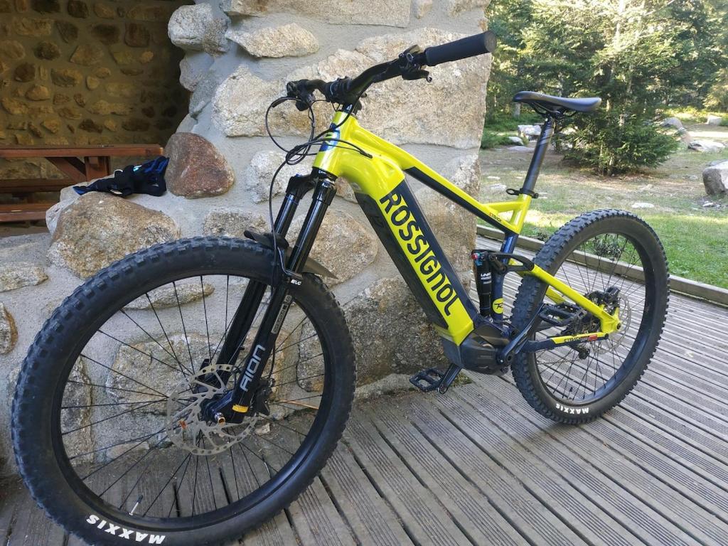 un vélo jaune garé à côté d'un mur de pierre dans l'établissement Gîte à CHALMAZEL équipé, dans hameau calme, à Mermond