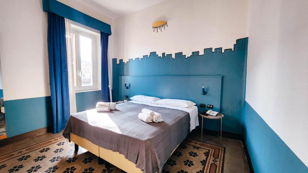 - une chambre bleue avec un lit et des serviettes dans l'établissement Hotel Bello by Ostello Bello, à Finale Ligure