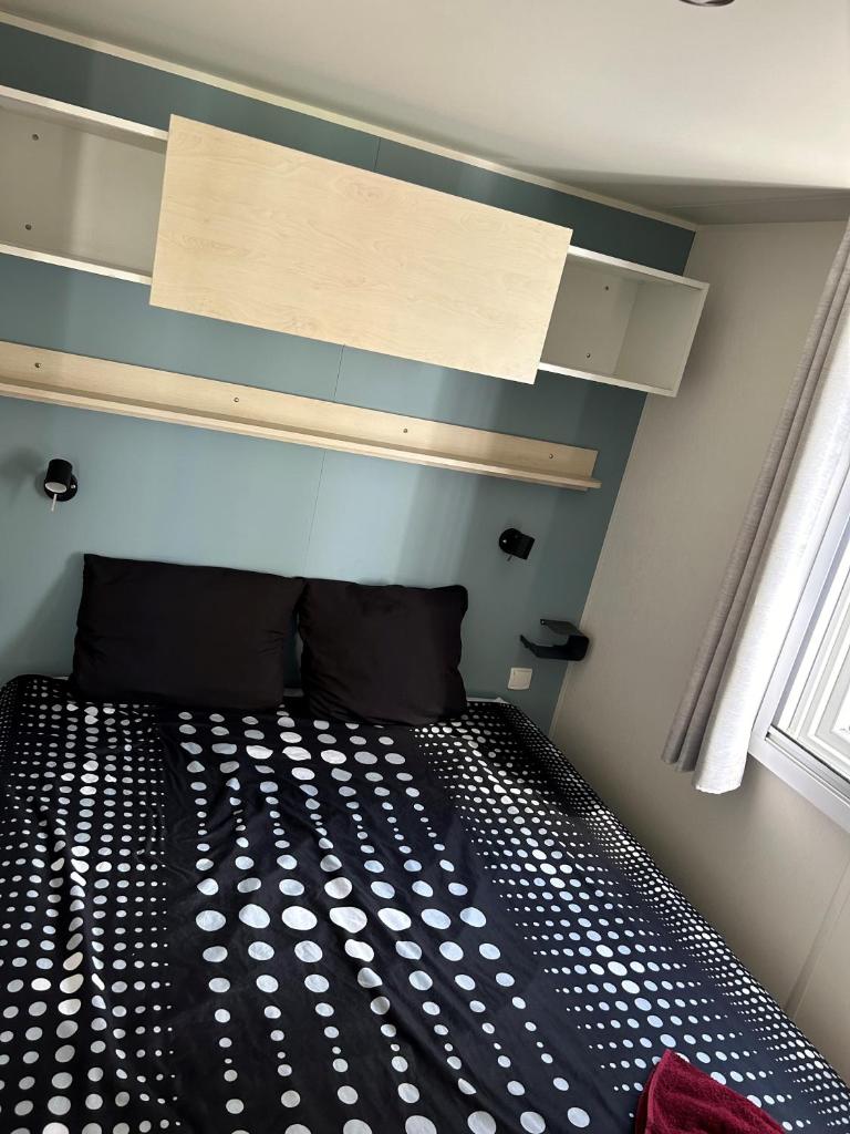 une chambre avec un lit noir et blanc et une fenêtre dans l'établissement Mobil-home 3 ch camping TOHAPI, à Port-la-Nouvelle