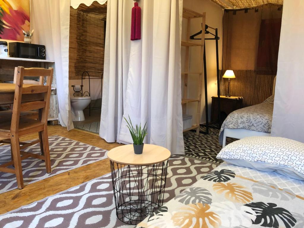 Cette chambre comprend un lit et une table avec une plante. dans l'établissement Les lodges de phanou Tente lodge, à Prissac