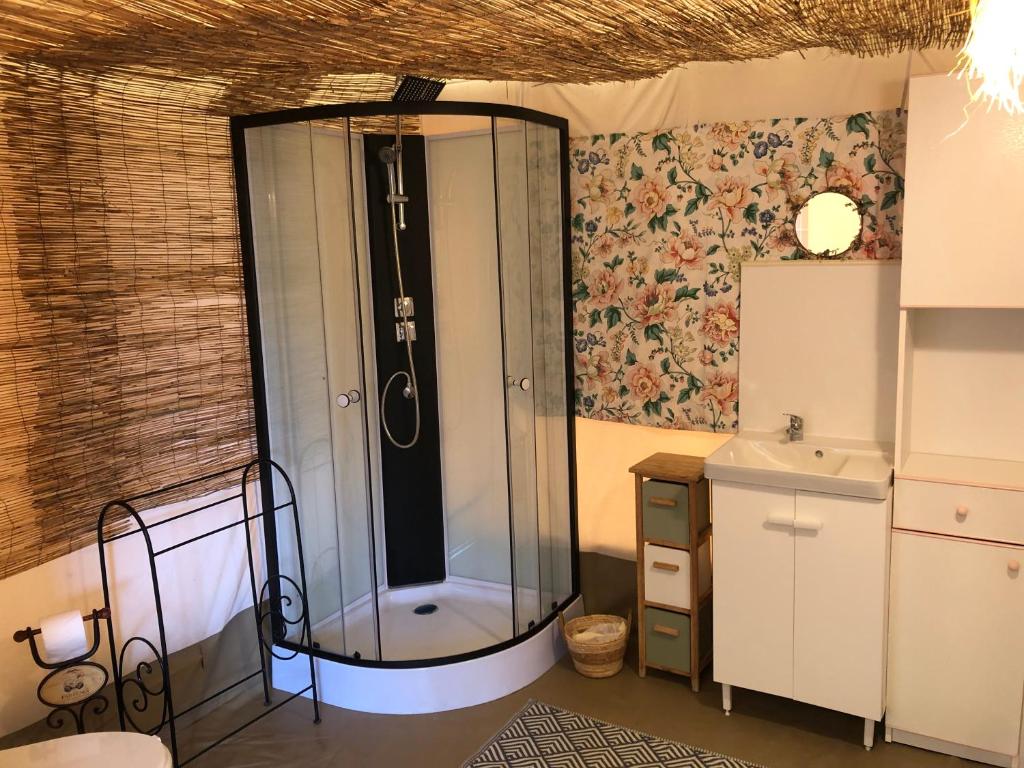 une douche en verre dans une salle de bain avec un lavabo dans l'établissement Les lodges de phanou Tente lodge, à Prissac