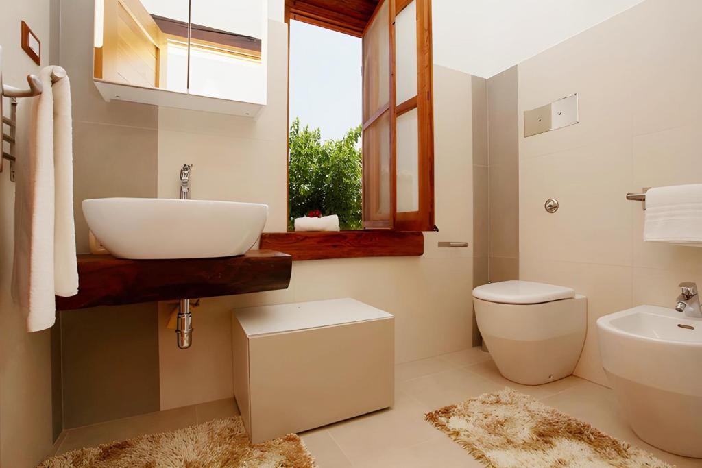 une salle de bain avec un lavabo et des toilettes et une fenêtre dans l'établissement Villa 2 Pini, à Alcamo