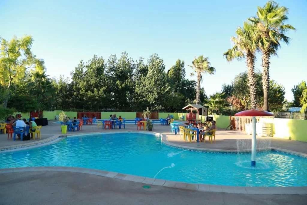 - une piscine avec des tables et des chaises dans l'établissement Camping 4 étoiles - Piscine - ccaffbg, à Villeneuve-lès-Béziers