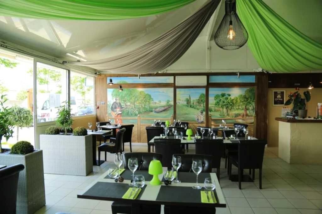 un restaurant avec des tables, des chaises et un auvent vert dans l'établissement Camping 4 étoiles - Piscine - ccaffbg, à Villeneuve-lès-Béziers
