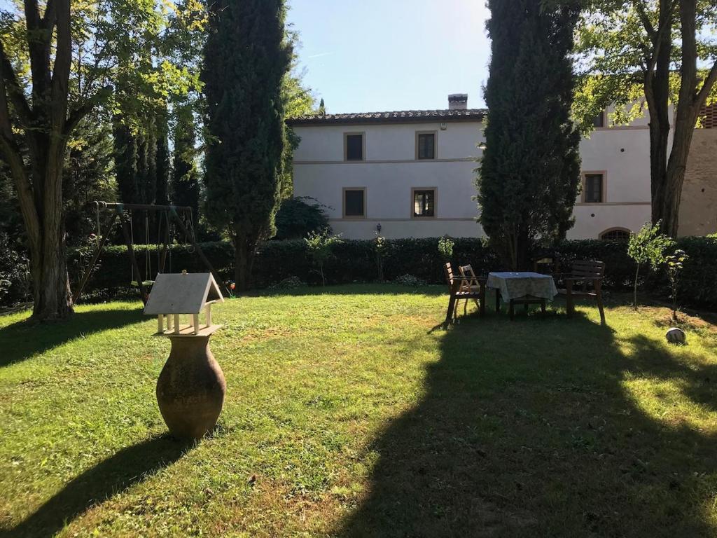 une cour avec un grand vase dans l'herbe dans l'établissement Casale Molin Bianco nelle colline del Chianti, à Castellina Scalo