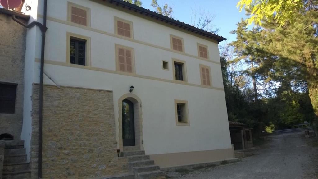 un grand bâtiment blanc avec un escalier devant dans l'établissement Casale Molin Bianco nelle colline del Chianti, à Castellina Scalo
