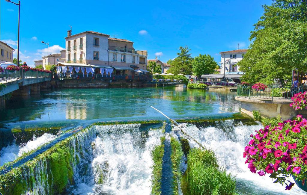 une rivière avec cascade dans une ville fleurie dans l'établissement Pet Friendly StaCaravan, à Entraigues-sur-la-Sorgue