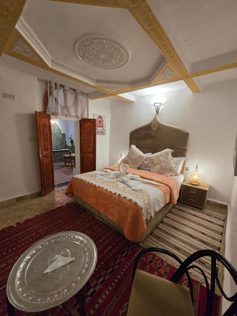 une chambre avec un grand lit et une table dans l'établissement Riad Mounadim Fes, à Fès