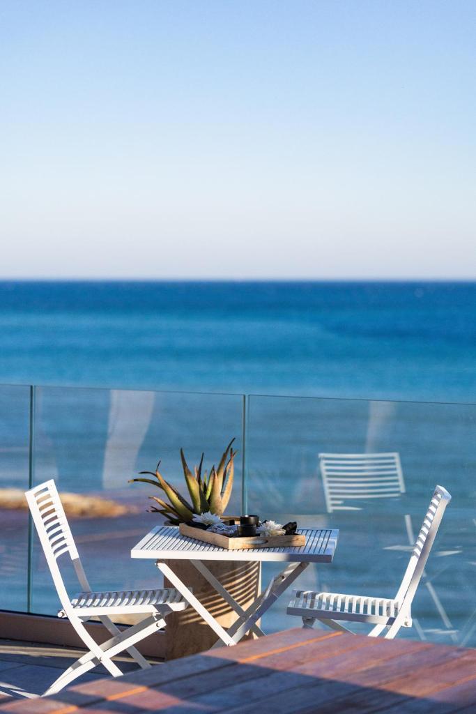 - une table avec des chaises et une plante en pot sur la plage dans l'établissement Baba Residences, à Alassio