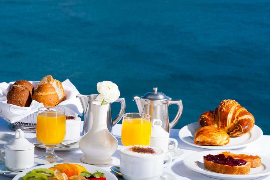 - une table avec petit-déjeuner composé de croissants et de jus d'orange dans l'établissement Hotel Casa Celestino, à Ischia