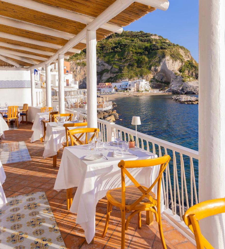 un restaurant avec des tables et des chaises et une vue sur l'océan dans l'établissement Hotel Casa Celestino, à Ischia