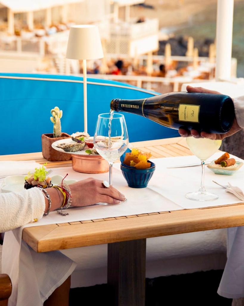 une personne versant un verre de vin sur une table dans l'établissement Hotel Casa Celestino, à Ischia