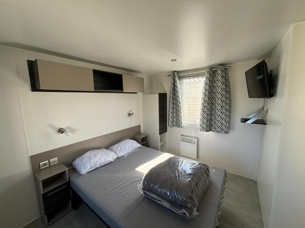 une chambre avec un lit avec deux oreillers dessus dans l'établissement Lodge du Sangla Mobil Home premium Village Vacances 4 étoiles Lège Cap Ferret, à Lège-Cap-Ferret