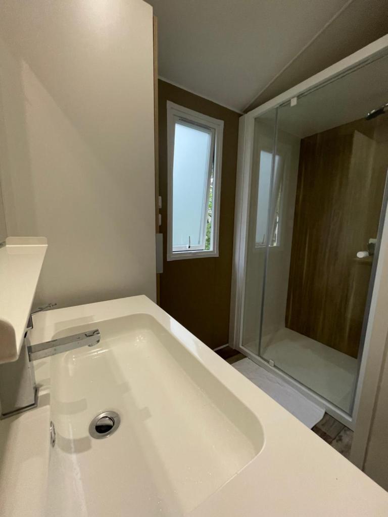 La salle de bains est pourvue d'une grande baignoire blanche et d'une douche. dans l'établissement Mobilhome bord du lac, à Parentis-en-Born 6 autres photos