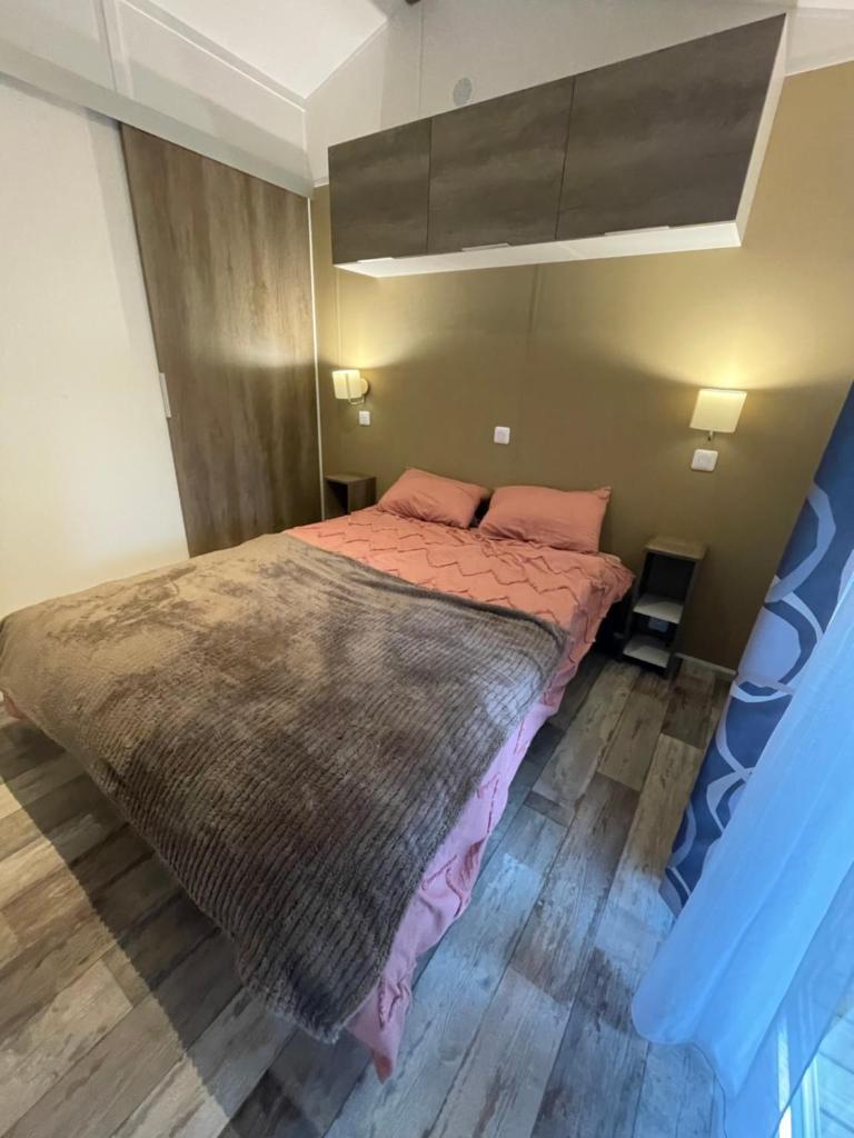 - une chambre avec un grand lit et des draps roses dans l'établissement Mobilhome bord du lac, à Parentis-en-Born