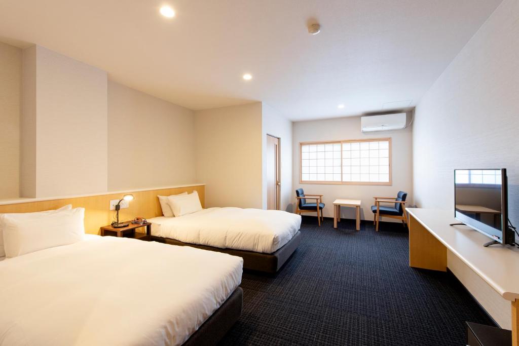 une chambre d'hôtel avec deux lits et une télévision à écran plat dans l'établissement Unzen Iwaki Ryokan, à Unzen