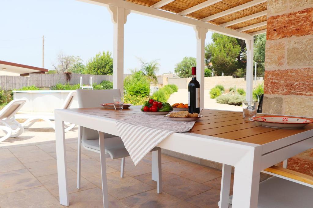 une table blanche et des chaises sur une terrasse dans l'établissement Villetta Marechiaro, à Marina di Pescoluse