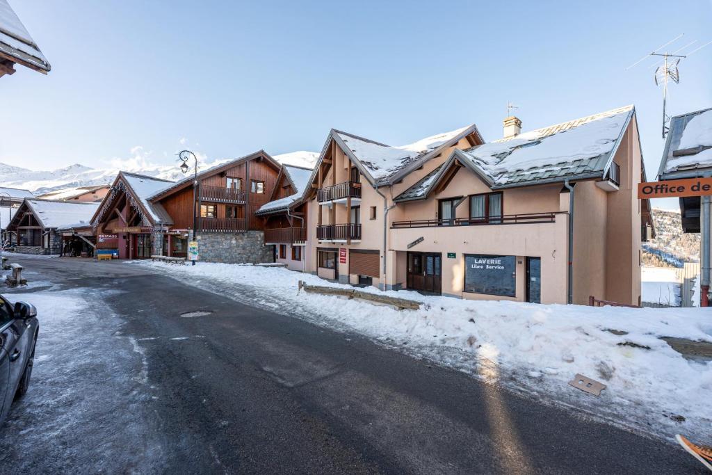 une rue enneigée dans un village avec des bâtiments dans l'établissement La Croix du Sud, à Valmeinier