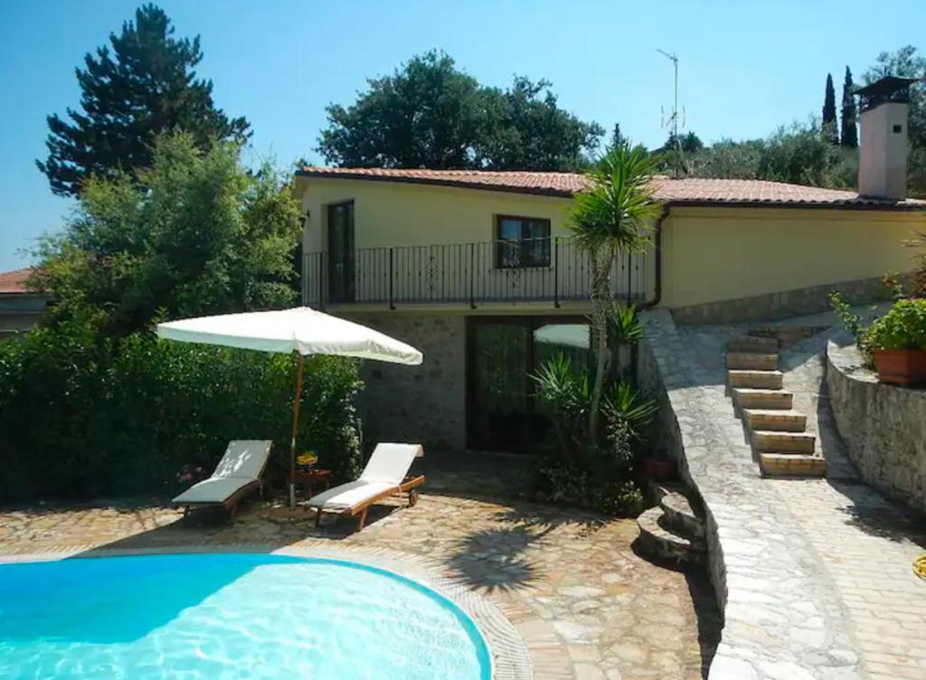 - une piscine avec un parasol et une maison dans l'établissement Villa Migi, à Archi