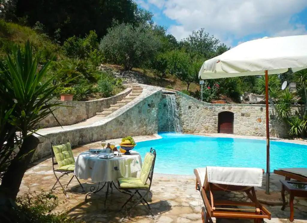 un patio avec une table et des chaises à côté d'une piscine dans l'établissement Villa Migi, à Archi 7 autres photos