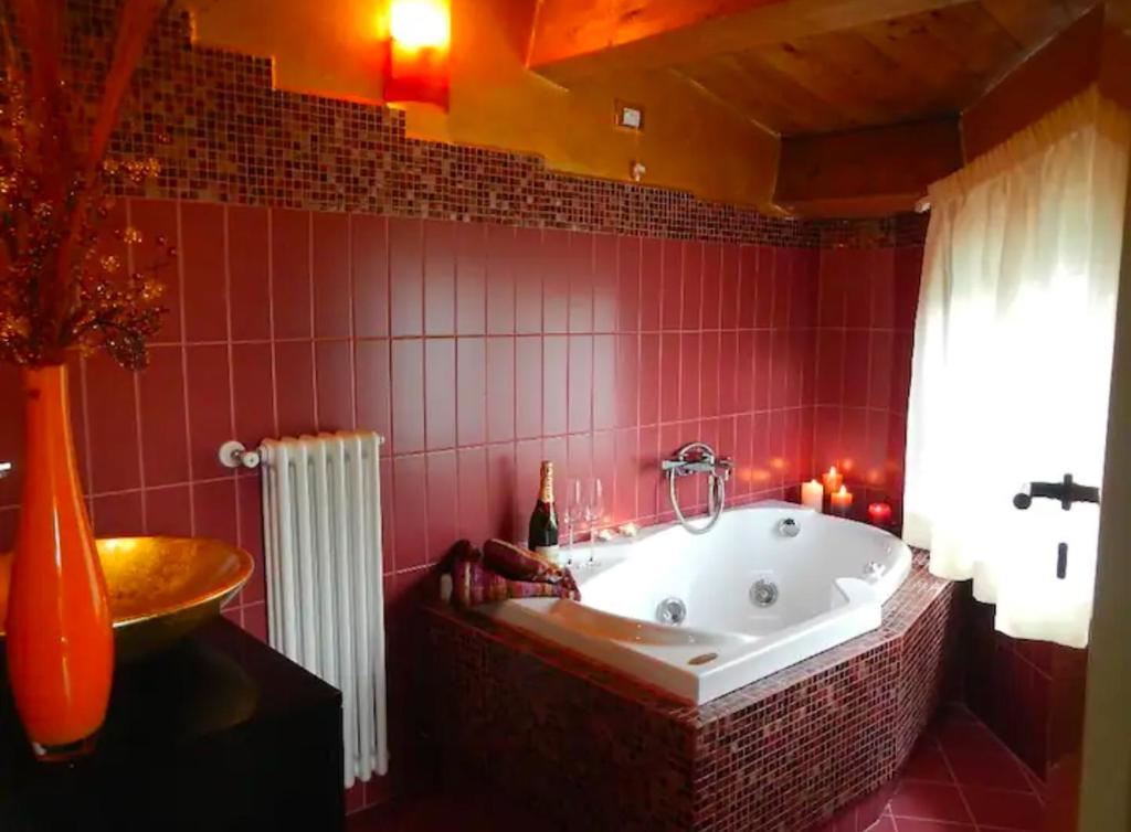 La salle de bains est pourvue d'une baignoire et d'un mur en carrelage rouge. dans l'établissement Villa Migi, à Archi