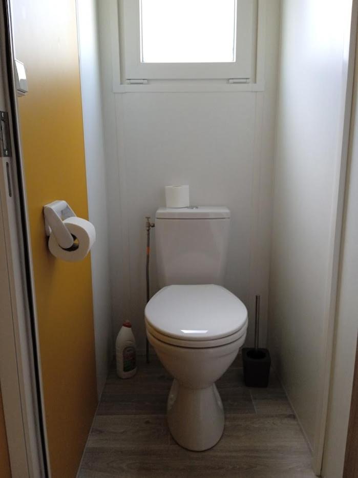 La salle de bains est pourvue de toilettes blanches et d'une fenêtre. dans l'établissement MOBIL-HOME TOUT CONFORT, 3 CHAMBRES, Domaine de Kerlann, à Pont-Aven 23 autres photos