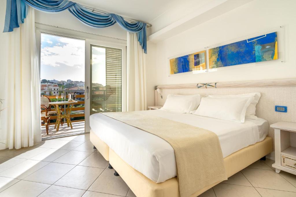 une chambre avec un grand lit et un balcon dans l'établissement Elaia Garden Hotel, à Sperlonga