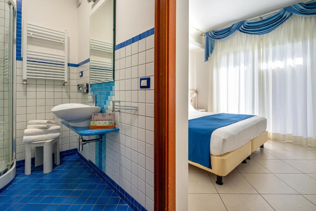 - une salle de bains bleue et blanche avec un lit et un lavabo dans l'établissement Elaia Garden Hotel, à Sperlonga