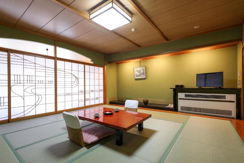 un salon avec une table et une télévision dans l'établissement 赤湯温泉 丹泉ホテル, à Nanyo