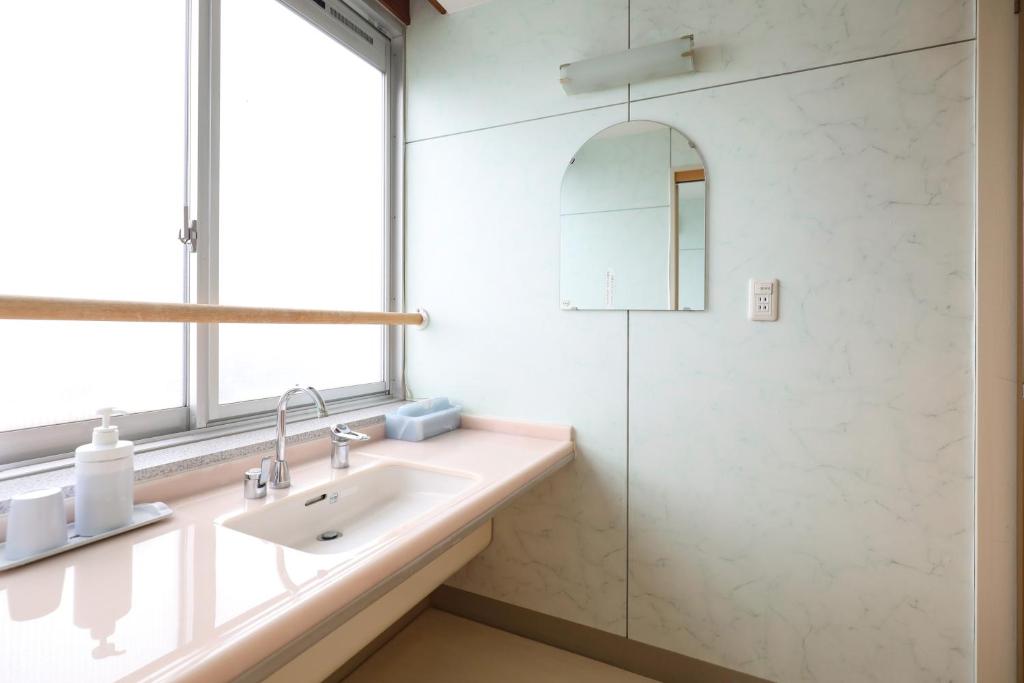 une salle de bain avec un lavabo et une douche dans l'établissement 赤湯温泉 丹泉ホテル, à Nanyo