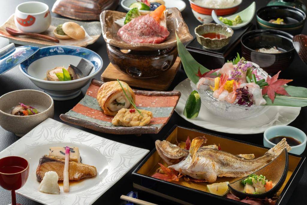 une table avec de nombreuses assiettes de nourriture dessus dans l'établissement Ikkyu -Seaside Hotel-, à Tsuruoka