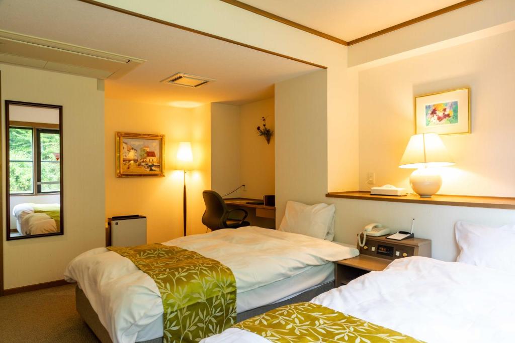 une chambre d'hôtel avec deux lits et un miroir dans l'établissement Suizansou, à Toyooka
