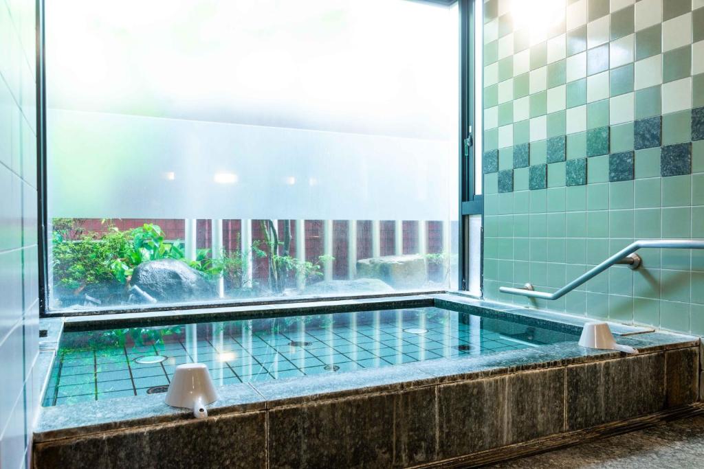 une salle de bain avec baignoire et une grande fenêtre dans l'établissement Suizansou, à Toyooka