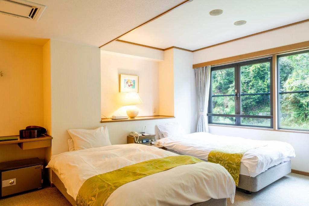 deux lits dans une chambre avec une fenêtre dans l'établissement Suizansou, à Toyooka