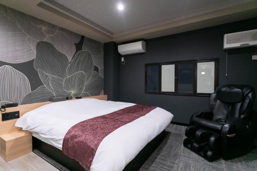 une chambre avec un lit et une chaise dans l'établissement Hotel TEMARI Matsumoto, à Matsumoto