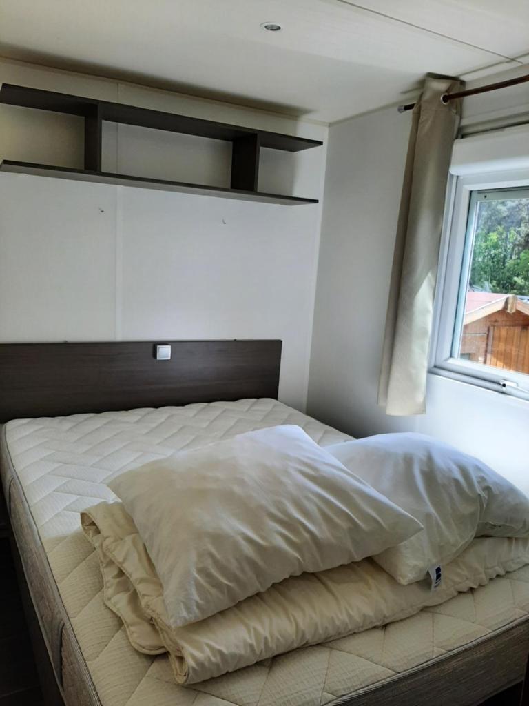 un lit dans une chambre avec une fenêtre dans l'établissement Mobilhome Mobil home Cap ferret, à Claouey