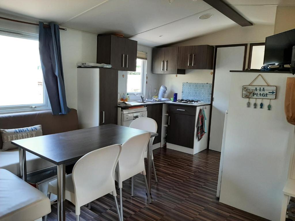 une petite cuisine avec une table et un réfrigérateur dans l'établissement Mobilhome Mobil home Cap ferret, à Claouey