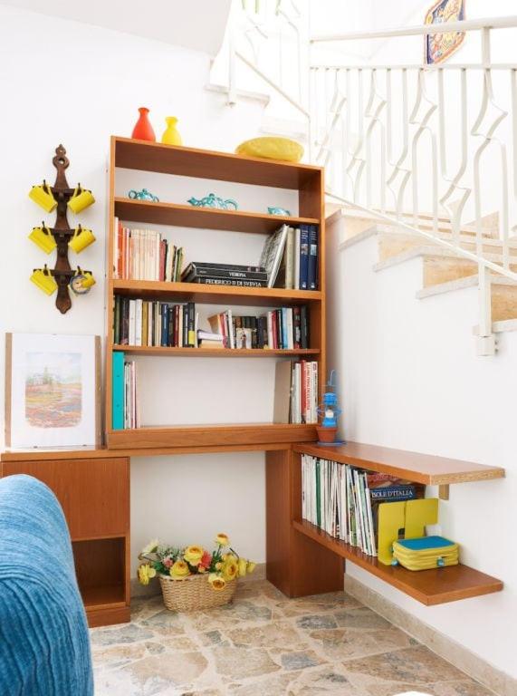 une étagère à livres à côté d'un escalier avec des livres dans l'établissement Villa Le Terrazze Blu by Sicily Travelling Villas, à Castellammare del Golfo