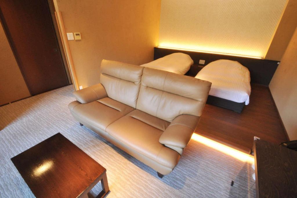 - un salon avec un canapé en cuir et un lit dans l'établissement Aura Tachibana, à Hakone