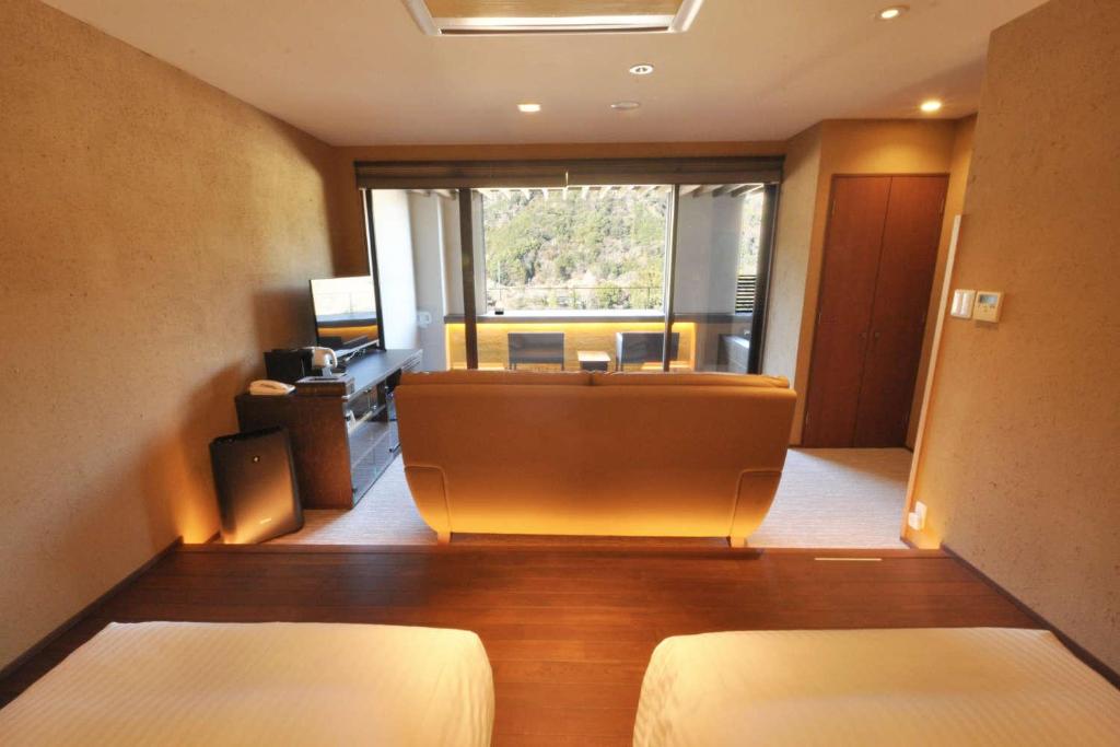 une chambre d'hôtel avec deux lits et une grande fenêtre dans l'établissement Aura Tachibana, à Hakone